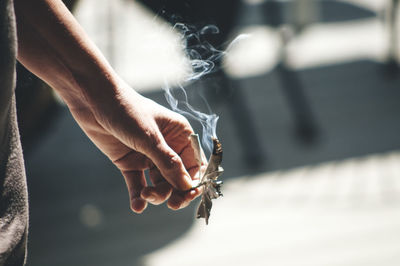 Cropped image of person holding burning sage leaves