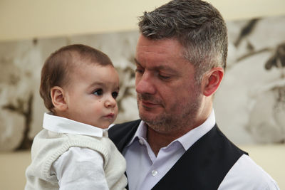 Close-up of father carrying son while standing at home