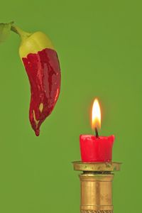 Close-up of lit candle against green background