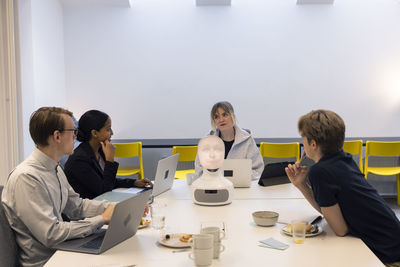 Business people discussing robot voice assistant during meeting