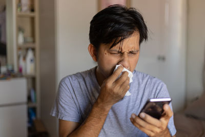 Portrait of man using mobile phone at home