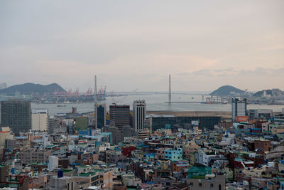 Cityscape by sea against sky during sunset