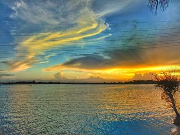 Scenic view of sea against cloudy sky at sunset