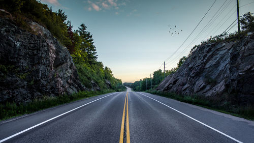 Empty road amidst rocks against sky