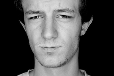 Close-up portrait of mid adult man against black background