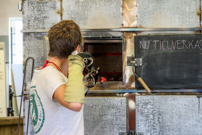 Side view of worker molding glass at factory