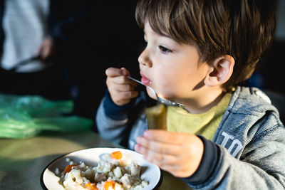 Cute boy having meal at home