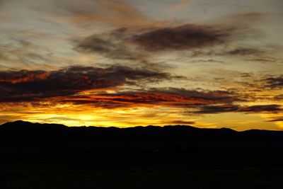 Silhouette landscape against dramatic sky during sunset