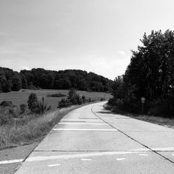 Road by trees against sky