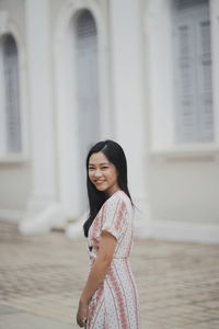 Side view of a smiling young woman standing outdoors