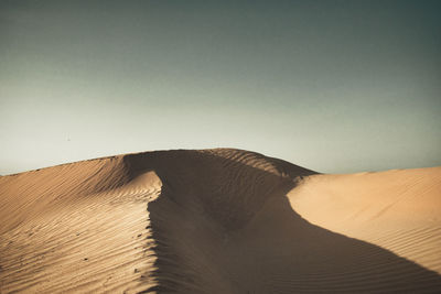 Sand dune in desert against clear sky