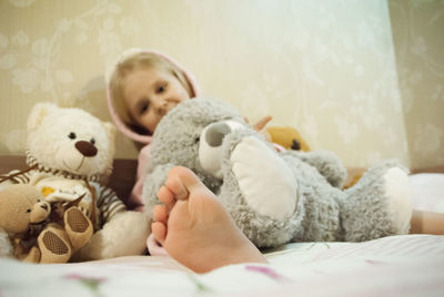 Portrait of girl with stuffed toy sitting on bed at home