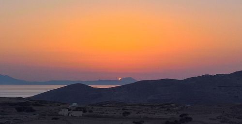 Scenic view of silhouette mountains against orange sky