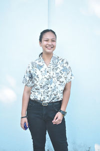 Portrait of smiling young woman standing against clear sky