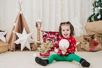 Cute girl playing with toys on bed at home