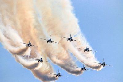 Low angle view of airshow against sky