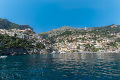 Scenic view of sea by buildings against blue sky