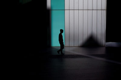 Side view of silhouette man walking against building with shadows 