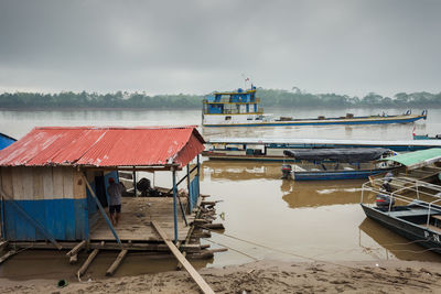 Fishing boat moored on pier at lake against sky