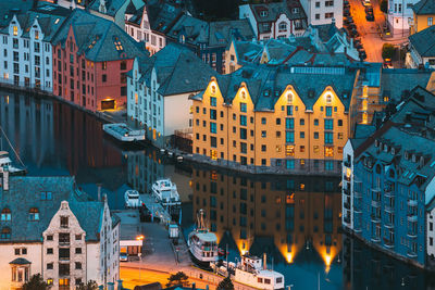 High angle view of illuminated buildings by canal in city