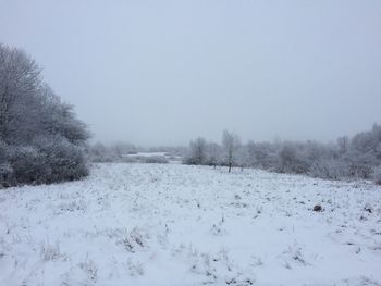 Snow covered field against clear sky