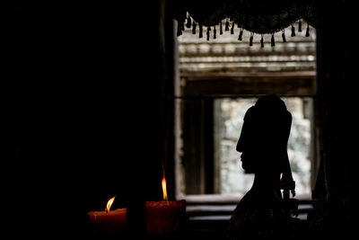 Silhouette man with arms raised in front of building