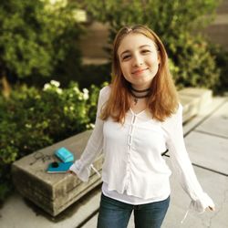 Portrait of smiling teenage girl standing at public park