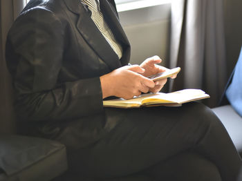 Midsection of businesswoman using mobile phone in office