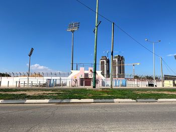 Road by buildings against blue sky