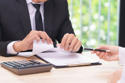 Midsection of man using mobile phone while sitting on table