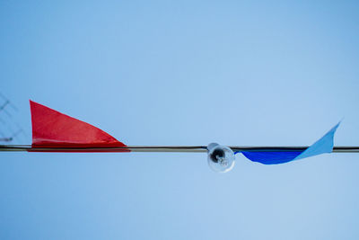 Directly below shot of bunting and light bulb against clear blue sky