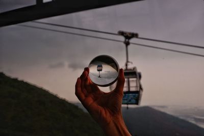 Close-up of person holding umbrella against sky