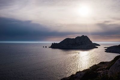 Scenic view of sea and cliff against sky during sunset