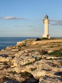 Lighthouse by sea against sky