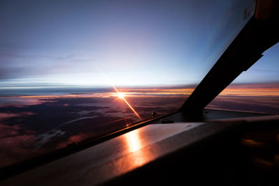 Cropped image of airplane wing against sky during sunset