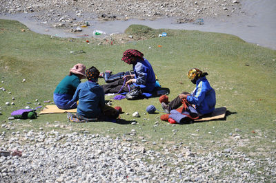 People knitting wool on field