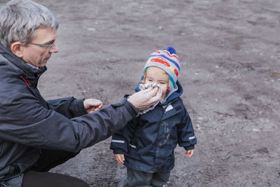 Grandfather cleaning nose of cute girl on road