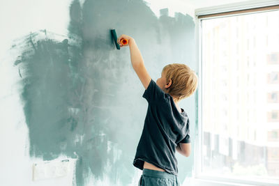 Side view of boy standing against the wall