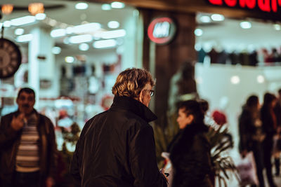 People standing in illuminated shopping mall at night