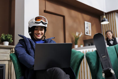 Portrait of young woman using laptop while sitting in office
