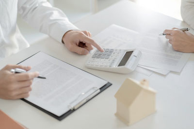 Midsection of man holding paper with text on table