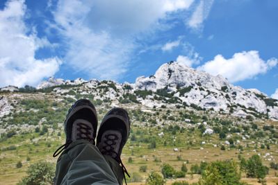 Low section of person on mountain against sky