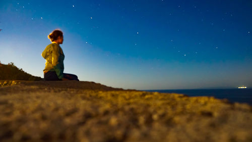 Young woman sitting against star field at beach