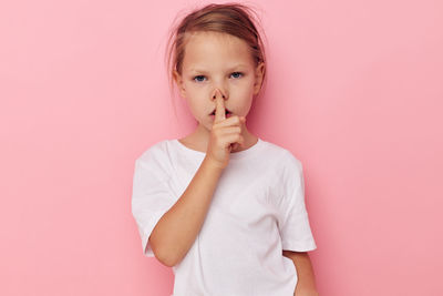 Portrait of cute girl gesturing against pink background