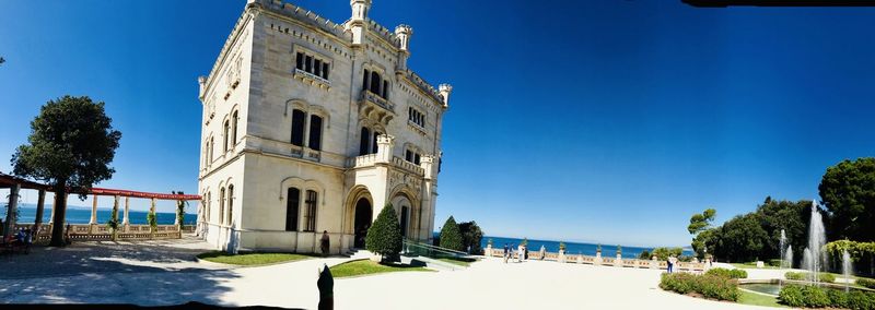 Buildings by sea against clear blue sky