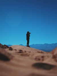 Man photographing at atacama desert against clear blue sky
