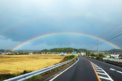 Rainbow over road against sky