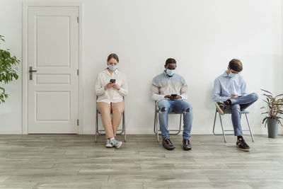 People wearing face masks sitting on chairs in waiting area