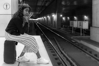 Woman sitting on railroad station platform