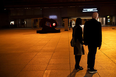 Rear view of people standing at railroad station